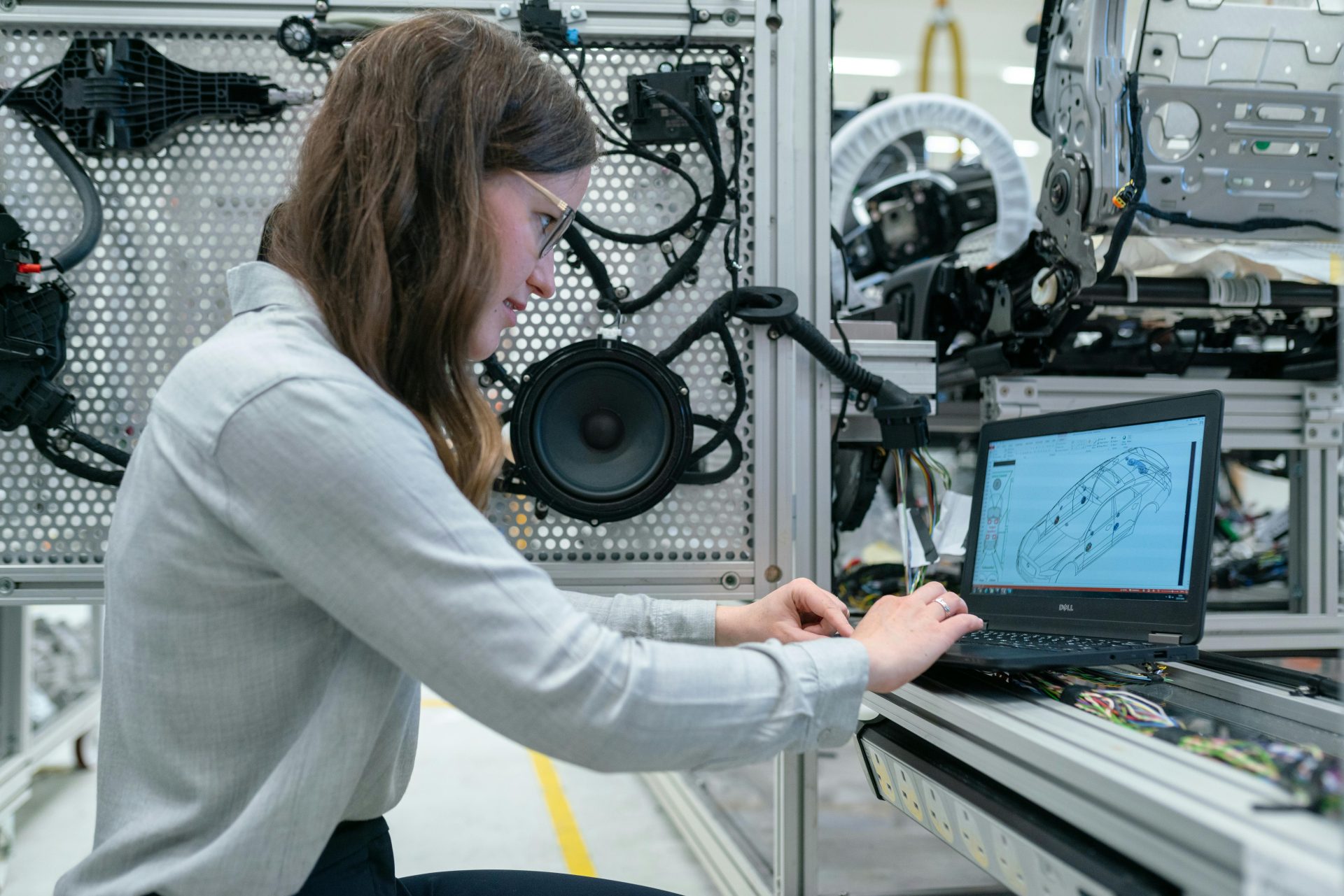 Mujer realizando una investigación de ingeniería en un taller de sistemas de sonido utilizando una computadora portátil.